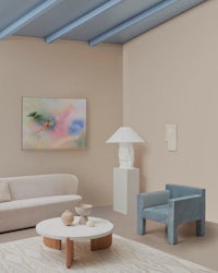 a living room with white furniture and a painting on the wall