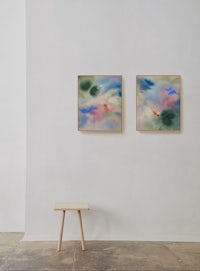 two paintings hanging on a wall next to a stool
